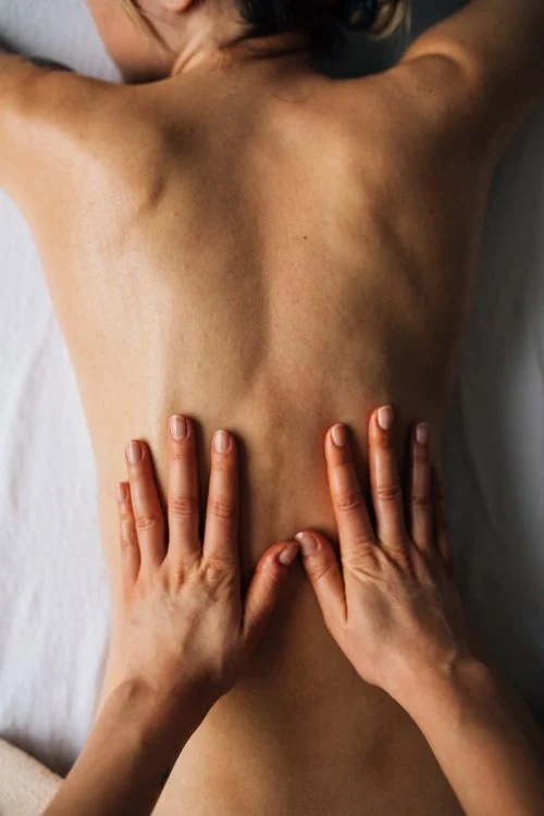 A close-up of hands working on a person's back